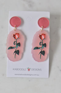 Pair of red rose perspex drop earrings on Kaboodle Designs card, front view
