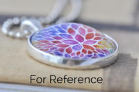 Close-up of floral pendant necklace showing silver-toned bezel and ball chain