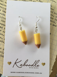 Pair of yellow resin pencil dangle earrings with brown tips on a Kaboodle Designs card