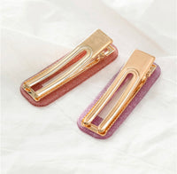 Two glitter acrylic barrette clips shown open from behind, displaying gold-tone hinge mechanism