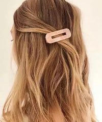 Rectangular acrylic barrette worn in wavy hair, half-up style