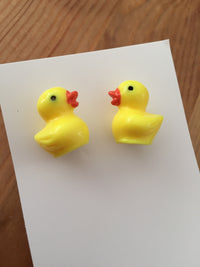 Pair of yellow 3D resin rubber duck stud earrings on white card, front view
