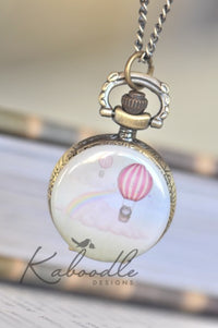 Hot air balloon pocket watch necklace with pink balloon, rainbow and clouds design