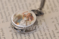 Pocket watch pendant partly open showing the Alice illustration lid and case detail