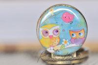 Close-up of owl and bird pendant artwork on pocket watch necklace