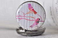 Close-up of the bird art pocket watch pendant design with two birds on pink branches