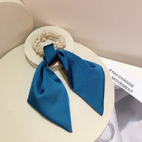 Royal blue fabric scrunchie with faux pearl cluster and long bow tails, top view