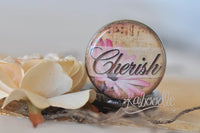 Close-up of 'Cherish' script pendant lid with pink daisy and vintage background