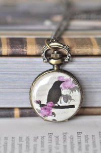 Bronze pocket watch necklace with a black bird silhouette and pink roses design