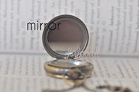 Inside view of pocket watch necklace lid featuring a small round mirror