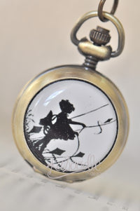 Close-up of antique brass pocket watch necklace with silhouette of girl flying a kite