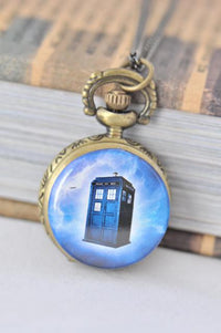 Small brass pocket watch necklace with a glowing blue police box design on the front cover