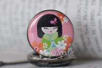 Close-up of kokeshi doll pendant artwork with pink and orange florals