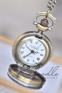 Open pocket watch necklace showing white clock face with Roman numerals and Quartz movement