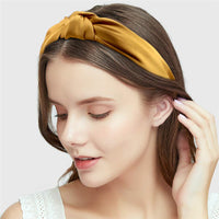 Model wearing a mustard yellow knotted headband styled back from the face