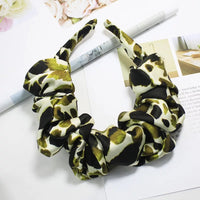 Ruffled animal-print fabric headband in cream, olive-green and black, laid flat