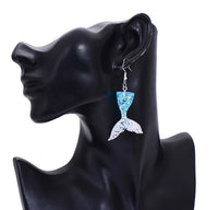 Blue and silver glitter mermaid tail earring shown worn on ear, close-up angle