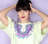 Model wearing purple hoop drop earrings with a printed cat-face necklace