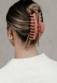 Model wearing a large claw clip in a twisted updo, back view of hair