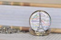 Close-up of Paris map and Eiffel Tower pocket watch pendant on books