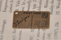 Close-up of the postcard charm showing 'I Love You' script and postcard stamp detail