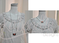Envelope necklace worn on a mannequin, front view and close-up on ruffled collar