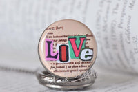 Love dictionary pocket watch pendant resting on a book