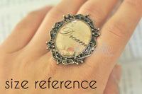 Similar filigree cameo ring worn on hand reading 'Dream', shown for size reference