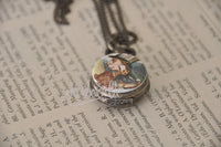 Mad Hatter pocket watch necklace resting closed on open book pages