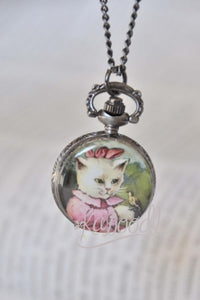 Pocket watch necklace featuring a white kitten in a pink bonnet illustration on the front cover