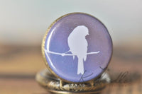 Bird silhouette pocket watch pendant against a purple night sky design