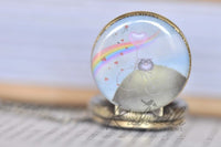 Close-up of bicycle, rainbow and heart balloon design on pocket watch pendant