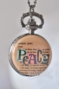 Pocket watch necklace with cut-out 'Peace' lettering over a dictionary definition, on a bronze-tone case
