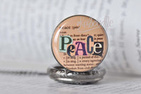 Close-up of 'Peace' pocket watch pendant with colourful lettering over vintage dictionary text