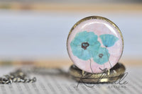 Close-up of blue poppy flower design on pocket watch pendant