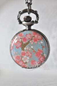 Cherry blossom pocket watch necklace with pink floral design on antique-toned case