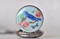 Close-up of blue bird and pink rose design on pocket watch pendant cover