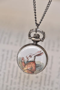 White Rabbit pocket watch necklace pendant hanging closed against an open book