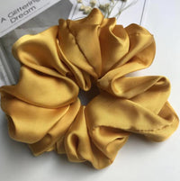 Close-up top view of mustard yellow giant scrunchie showing fabric texture and folds